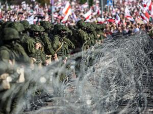 Belarusian servicemen stand behind a barbed wire fence during an opposition supporters rally protesting against disputed presidential elections results in Minsk on August 30, 2020. Tens of thousands of opposition supporters marched through Minsk on August 30, calling for an end to strongman Alexander Lukashenko's rule amid a heavy security presence and despite dozens of arrests. Belarus protests have entered a third week since the disputed presidential election on August 9 in which Lukashenko claimed victor
