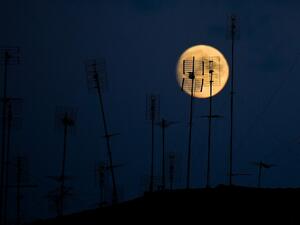 Television antennas atop a building are pictured against the moon on August 31, 2020 in Rome. Tiziana FABI / AFP