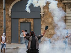 A protester uses a tennis racket to repel a tear gas canister during clashes with security forces amidst an anti-government demonstration in the centre of Lebanon's capital Beirut during on September 1, 2020. AFP