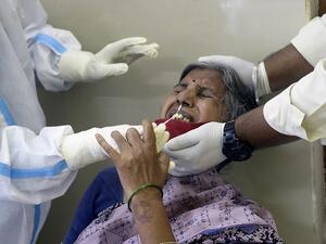 A health worker (L) wearing a Personal Protective Equipment (PPE) suit collects a swab sample from a woman to test for the Covid-19 coronavirus at a primary health centre in Hyderabad on September 3, 2020. NOAH SEELAM / AFP