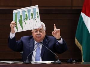 Palestinian president Mahmud Abbas holds a placard showing maps of (L to R) historical Palestine, the 1947 United Nations partition plan on Palestine, the 1948-1967 borders between the Palestinian territories and Israel, and a map of US President Donald Trump's proposal for a Palestinian state under his new peace plan, as he speaks in the West Bank's Ramallah on September 3, 2020, as he meets by video conference with representatives of Palestinian factions gathered at the Palestinian embassy in Beirut in ra
