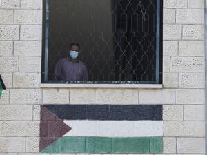 A Palestinian teacher, wearing a protective face mask, looks on from a window on the first day of school in the village of Salem east of Nablus in the occupied West Bank on September 6, 2020, during the coronavirus pandemic. JAAFAR ASHTIYEH / AFP