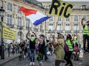 A protester holds a sign reading "RIC" for "Citizens Initiative Referendum" and another wave a French national flag as they take part in a demonstration called by the "Yellow Vest" (Gilets Jaunes) movement in Bordeaux, southwestern France on September 12, 2020. Philippe LOPEZ / AFP