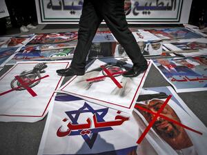 A demonstrator walks on pictures laid out on the ground depicting X-marks over the faces of Bahrain's King Hamad bin Isa al-Khalifa and Abu Dhabi Crown Prince Sheikh Mohammed bin Zayed al-Nahyan (shown before an Israeli flag with the Arabic word "traitor" superimposed), during a protest against the United Arab Emirates' and Bahrain's decisions to normalise relations with Israel, in Gaza City on September 15, 2020. Palestinian leaders had earlier called for demonstrations against the "shameful" deals the Uni