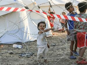 Youngsters of migrant families stand behind barbwire at a quarantine area in the new temporary camp near Mytilene on the Greek island of Lesbos, as more than 200 people were diagnosed with COVID-19, on September 19, 2020.  MANOLIS LAGOUTARIS / AFP