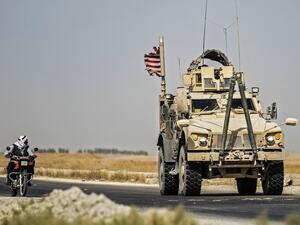 A Syrian man rides a motorcycle past a US military vehicle patrolling the town of Tal Tamr, in Syria's northeastern Hasakeh province, on September 21, 2020. Delil SOULEIMAN / AFP
