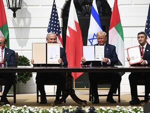 The four leaders hold up the signed copies of the Abraham Accords - they signed one in English, one in Hebrew and two in Arabic (AFP)