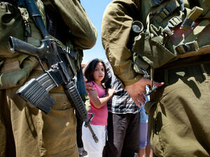 A Palestinian girl faces Israeli soldiers (Shutterstock)	