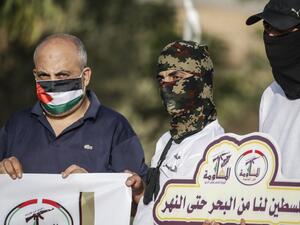 Masked Palestinians of the Popular Resistance Committees hold signs on the 21st anniversary of the group and protesting against the normalisation deal with the UAE and Bahrain, on September 28, 2020 in Rafah in the southern Gaza Strip. SAID KHATIB / AFP