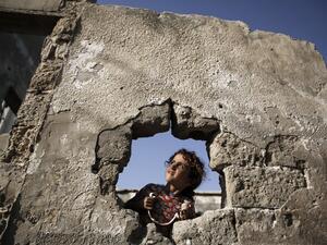 A Palestinian girl is pictured behind a whole at her destroyed family's house in Gaza City, on October 8, 2020. MOHAMMED ABED / AFP