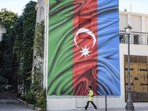 A woman walks past a building with a painting of the Azerbaijani flag on its wall in Baku on October 14, 2020, amid the ongoing military conflict between Armenia and Azerbaijan over the breakaway Nagorno-Karabakh region. TOFIK BABAYEV / AFP