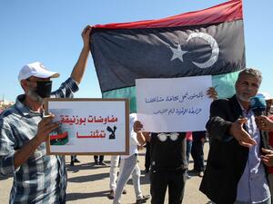 Libyans lift placards during a demonstration to protest upcoming talks between the country's two rival administrations, and demand relying on the constitution to solve the conflict, in front of the headquarters of the United Nations Mission in the city of Janzour, west of the Libyan capital, on October 14, 2020. (AFP/File)