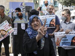 Palestinian protesters hold up signs in solidarity with hunger-striking Palestinian detainee held by Israel Maher al-Akhras and other Palestinians in Israeli prisons during a demonstration in the centre of the flashpoint West Bank city of Hebron on October 21, 2020. (AFP)