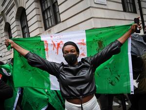 A protester holds a flag stained with fake blood during a demonstration outside the Nigerian High Commission against police brutality in Lagos in London on October 21, 2020. UN Secretary General Antonio Guterres called Wednesday for an end to what he called "brutality" by police in Nigeria, which has been rocked by two weeks of protests. Guterres said gunmen that opened fire on peaceful protesters Tuesday evening in Lagos caused "multiple deaths" and many injuries. Daniel LEAL-OLIVAS / AFP