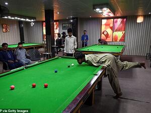 Mr Ikram crooks his neck to take aim and bends over to sink a rebound shot. (AFP)