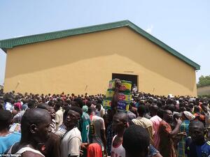 People carry bags of food on their heads during a mass looting of a warehouse in Abuja on Monday. (AFP)