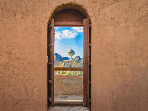 Narrow archway with old, heavy wooden doors opened to show the famous frankincense monument of Muscat, Oman  (Shutterstock)	