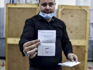 A poll station worker displays a cast "yes" ballot during the counting after a vote on a revised constitution ended at a station in Algeria's capital Algiers on November 1, 2020. RYAD KRAMDI / AFP