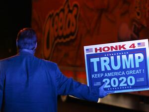 Under the blue light from a police car parked behind him, Andy Danevicius holds a Trump 2020 sign in front of a Cheetos truck as he protest the Nevada vote along with other Trump supporters outside Clark County Election Department on November 5, 2020, in North Las Vegas. Danevicius, who hails from Canada, said that he became a US Citizen last year to be able to vote in this election. Ronda Churchill / AFP