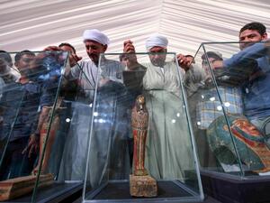 A picture shows statues and funerary masks on display during the unveiling of an ancient treasure trove of more than a 100 intact sarcophagi, at the Saqqara necropolis 30 kms south of the Egyptian capital Cairo, on November 14, 2020. Egypt announced the discovery of an ancient treasure trove of more than a 100 intact sarcophagi, the largest such find this year. The sealed wooden coffins, unveiled on site amid fanfare, belonged to top officials of the Late Period and the Ptolemaic period of ancient Egypt. Th