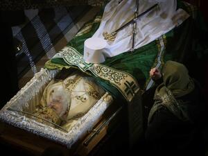 An orthodox faitfhul bends on the casket casket of late Serbian patriarch Irinej during his funeral service at Belgrade's cathedral, on November 21, 2020. Patriarch Irinej, the head of the Serbian Orthodox Church, died of coronavirus on November 20, 2020, three weeks after his unofficial second-in-command also succumbed to Covid-19, the church said. OLIVER BUNIC / AFP