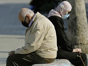 A man and a woman sit back to back on a bench as they enjoy a sunny day near the Beirut seaside promenade on November 24, 2020. JOSEPH EID / AFP