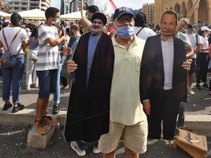 Man holds cut-outs of Hezbollah leader Hassan Nasrallah, left, and former foreign minister Gebran Bassil (AFP)
