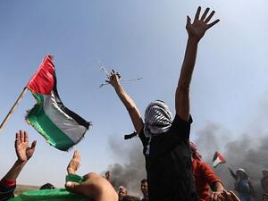 Palestinian demonstrators wave their national flag and shouts slogans against Israeli security forces during a protest on the Israel-Gaza border in the northern Gaza Strip on April 6, 2018. (AFP/Mohammed Abed)