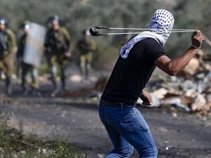 A Palestinian demonstrator uses a slingshot to hurl stones toward Israeli security forces during clashes with them following a weekly demonstration in the occupied West Bank village of Kfar Qaddum, on November 13, 2020. JAAFAR ASHTIYEH / AFP