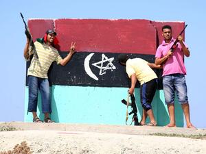 In this file photo taken in Tripoli on August 22, 2011, Libyan rebels stand in front of a freshly painted wall with the flag of Libya's monarchy, which ruled from independence in 1951 until overthrown by Moamer Kadhafi in 1969. Mahmud TURKIA / AFP