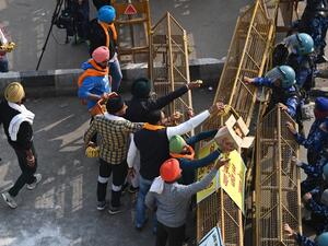 Farmers offer bananas and jaggery to the Indian security personnel at a road block stopping farmers from marching to New Delhi to protest against the central government's recent agricultural reforms at the Delhi-Uttar Pradesh state border in Ghazipur on December 1, 2020. Sajjad HUSSAIN / AFP