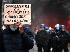 A protester holds a sign reading "Oppressors or oppressed, choose your side" in front of riot mobile gendarmes during a demonstration for 'social rights' and against the 'global security' draft law, which Article 24 would criminalise the publication of images of on-duty police officers with the intent of harming their 'physical or psychological integrity', in Paris, on December 5, 2020. Anne-Christine POUJOULAT / AFP