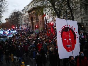 A protester holds a sign showing the French President Emmanuel Macron as a virus during a demonstration in Paris on december 12, 2020, against the 'global security' draft law. It is the third weekend of demonstrations in France during protests against a security bill currently going through French parliament, that would restrict publication of pictures showing the faces of police. Christophe ARCHAMBAULT / AFP
