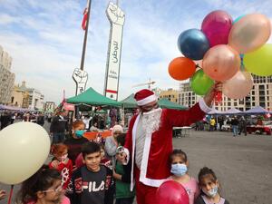 A Lebanese man wearing a Santa Claus outfit, entertains children at a Christmas market set up on Martyr's square, the epicentre of anti-government protests, in the capital Beirut's downtown district, on December 13, 2020. ANWAR AMRO / AFP
