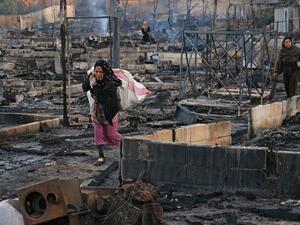 Syrian refugees salvage belongings from the wreckage of their shelters at a camp set on fire overnight in the northern Lebanese town of Bhanine on December 27, 2020, following a fight between members of the camp and a local Lebanese family. The United Nations refugee agency, UNHCR, confirmed a large fire had broken out in a camp in the Miniyeh region and said some injured had been taken to hospital, but did not provide an exact number. Ibrahim CHALHOUB / AFP