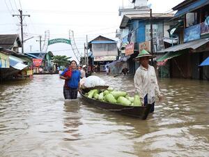 Residents use a boat to transport goods through floodwaters on a street in Hpa-an, the capital of Karen state, on Friday. (AFP Photo)