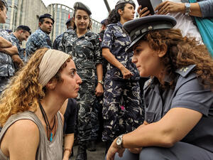 A protester faces off with a police officer during a sit-in on a main road in the Lebanese capital of Beirut, on the tenth day of anti-government demonstrations.  (Shutterstock)	