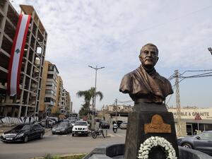 A photo taken on January 5, 2021 shows a Lebanese flag hanging on a building under construction behind the newly unveiled statue of Iran's most revered military commander, Qasem Soleimani, in the predominantly-Shiite Muslim Beirut southern suburb of Ghobeiry. Soleimani -- whom the US blamed for attacks on its interests in Iraq and elsewhere -- was killed in a US drone strike at Baghdad airport on January 3 last year, ratcheting up tensions between decades-old arch foes the United States and Iran. JOSEPH EID