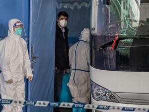 Vladimir G. Dedkov (C), a member of the World Health Organization (WHO) team investigating the origins of the Covid-19 pandemic, boards a bus following the team's arrival at a cordoned-off section in the international arrivals area at the airport in Wuhan on January 14, 2021. NICOLAS ASFOURI / AFP