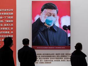 In this picture taken on January 15, 2021, a picture of China's President Xi Jinping with a face mask is displayed as people visit an exhibition about China’s fight against the COVID-19 coronavirus at a convention centre that was previously used as a makeshift hospital for patients in Wuhan. January 23 marks one year since the start of a 76-day lockdown of Wuhan, the central Chinese city where the coronavirus was first detected before sweeping across the world and killing more than two million people.  NICO