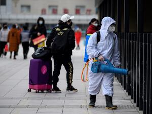 A worker disinfects the departure area of the Beijing railway station on January 27, 2021. NOEL CELIS / AFP