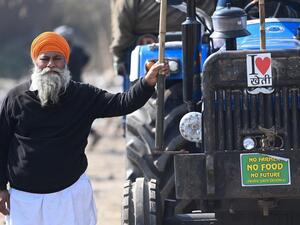 A farmer stands next to his tractor as they continue to protest against the central government's recent agricultural reforms at the Delhi-Haryana state border in Singhu on January 27, 2021. Money SHARMA / AFP