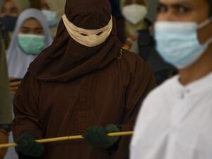 A member of the Sharia police (L) prepares to cane a man (R) accused of having gay sex in Banda Aceh on January 28, 2021. Aceh is the only region in the world's biggest Muslim-majority nation that imposes Islamic law -- known as Sharia -- with those found guilty of breaches often publicly whipped with a rattan cane. CHAIDEER MAHYUDDIN / AFP