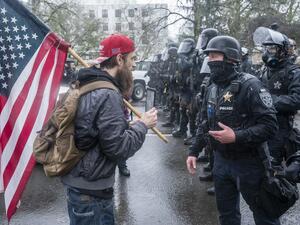 A supporter of President Trump speaks with riot police during a protest on January 6, 2021 in Salem, Oregon. Trump supporters gathered at state capitals across the country to protest today's ratification of Joe Biden's Electoral College victory over President Trump in the 2020 election. Nathan Howard/Getty Images/AFP