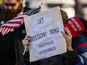  A supporter of President Donald Trump holds a MAGA hat and sign reading "Let freedom ring, investigate voter fraud" as conservative demonstrators gather at the Washington State Capitol on January 10, 2021 in Olympia, Washington. David Ryder / GETTY IMAGES NORTH AMERICA / Getty Images via AFP