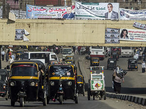 Egyptians drive rickshaws also known as "tuk-tuks" along a road displaying banners of parliamentary election candidates in the Imbaba district of the Egyptian capital, Cairo, Oct. 15, 2015. Photo by KHALED DESOUKI/AFP/Getty Images. 