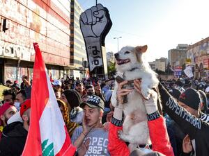 An anti-government protester holds a dog up in the air next to others chanting slogans during a demonstration in the centre of Lebanon's impoverished northern port city of Tripoli on January 31, 2021. Fathi AL-MASRI / AFP