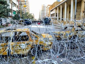 Security forces' vehicles are seen from behind barbed wire in the centre of Lebanon's impoverished northern port city of Tripoli on January 31, 2021. Fathi AL-MASRI / AFP