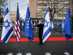 A Kosovo Albanian man takes pictures of Israeli's, US and Kosovo's flag displayed during a ceremony at the headquarters of the Foreign Ministry in Pristina on February 1, 2021. Kosovo and Israel established diplomatic ties on February 1, 2021, with the Muslim-majority territory recognising Jerusalem as the Jewish state's capital, putting it at odds with the rest of the Islamic world. In a ceremony held over Zoom in Jerusalem and Pristina, Israeli Foreign Minister and his counterpart from Kosovo signed a joi