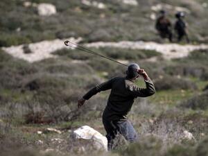 A Palestinian protester hurls rocks at Israeli security forces, during clashes with them following a demonstration against the expansion of settlements, near the village of Beit Dajan east of Nablus, in the occupied West Bank, on February 6, 2021. International law regards all settlements built on occupied Palestinian land, whether public or privately owned, as illegal. JAAFAR ASHTIYEH / AFP